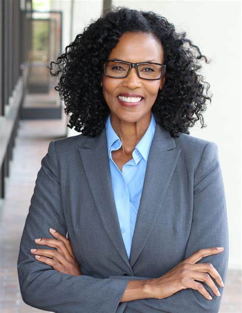 rochelle a curly haired 37 year old woman with glasses wearing business casual attire posing for a picture